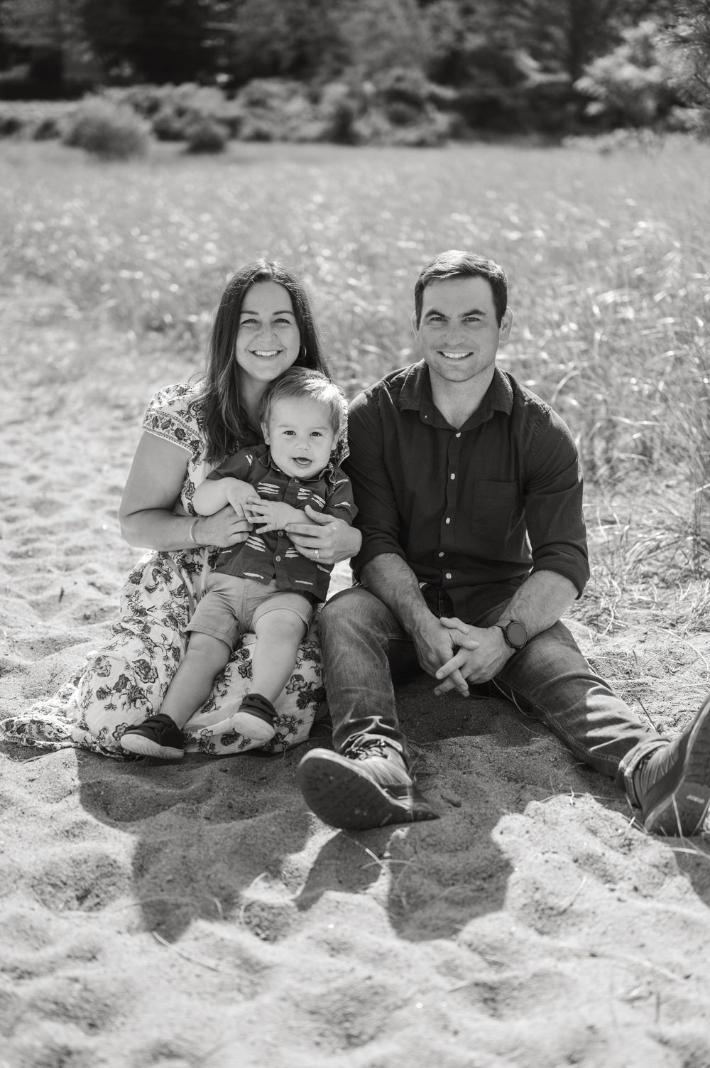 A series of black and white photos showing a couple and child relaxing together in a meadow or field setting.