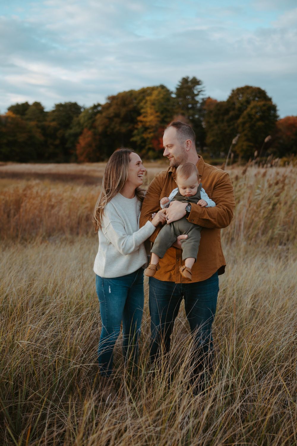 Family shares joyful moment together in autumn field with tall grass.