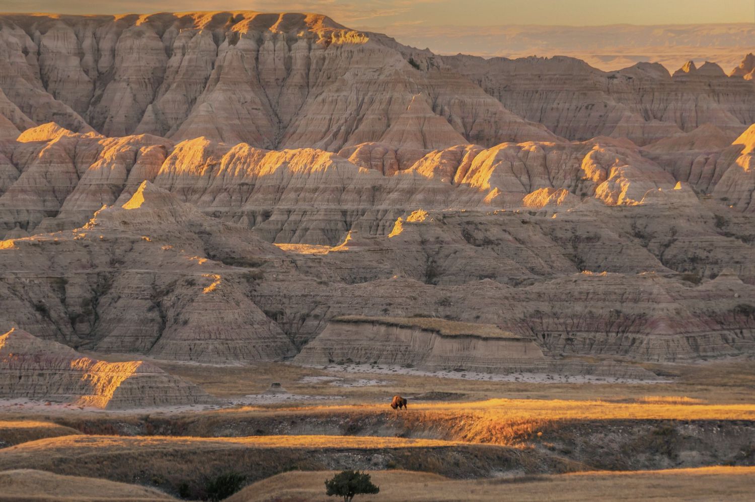 Dramatic golden light illuminates layered rock formations in Badlands National Park.