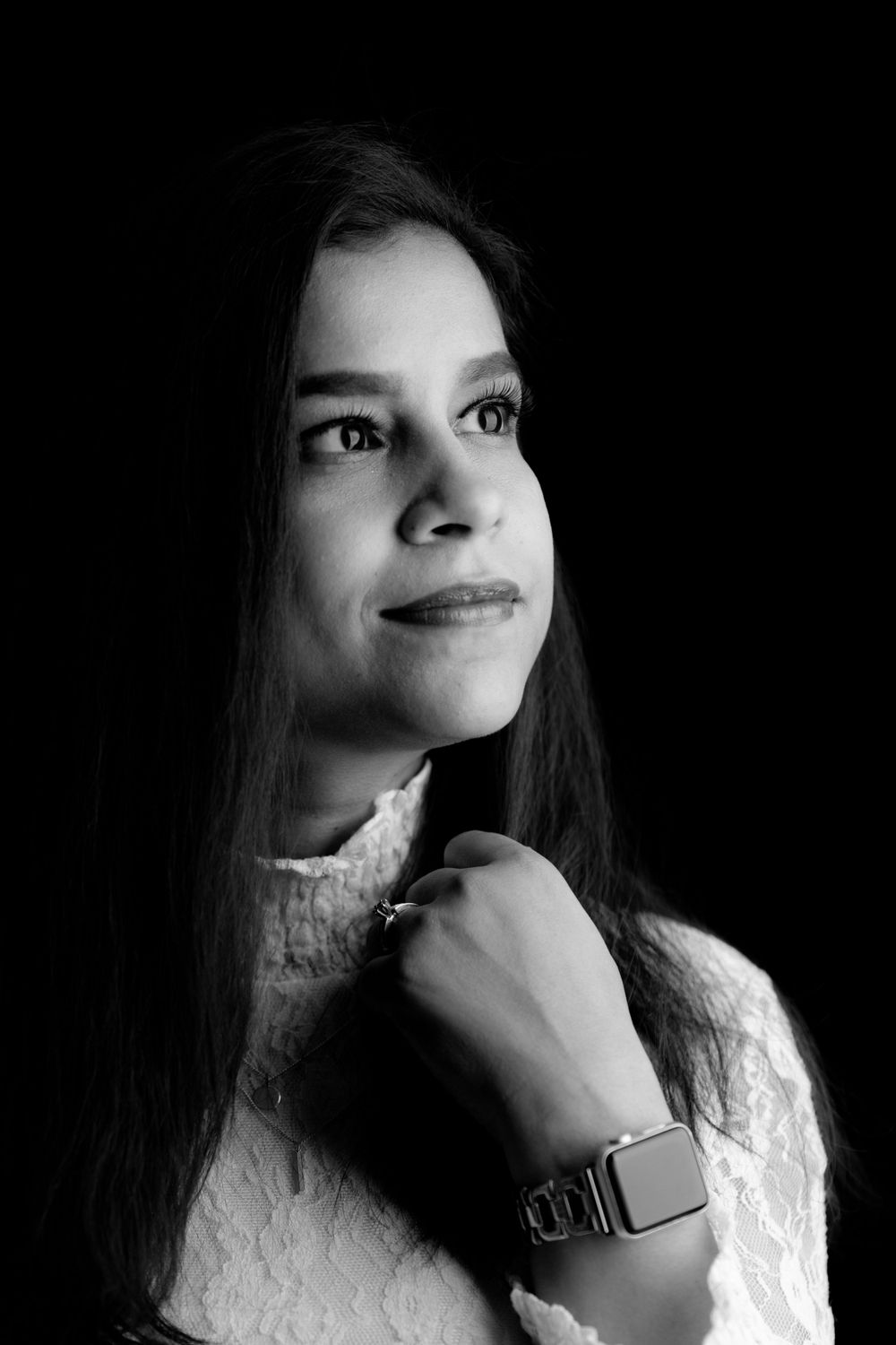 Black and white portrait with soft lighting highlighting elegant lace details and smartwatch.