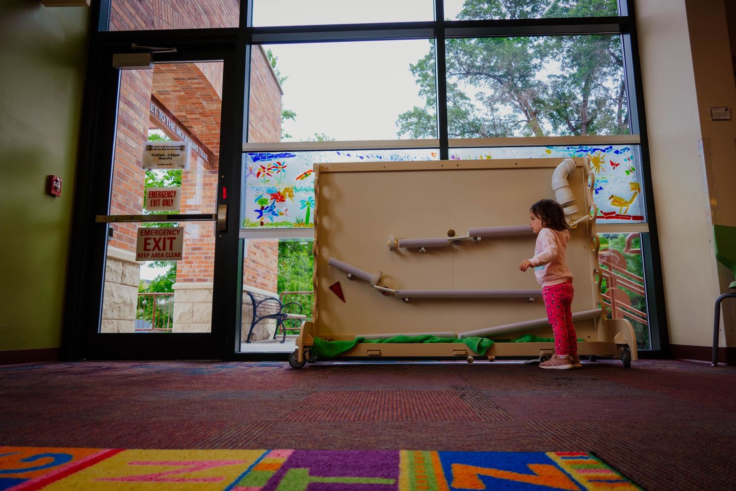 Colorful children's play area with large windows and carpet squares in a learning center.