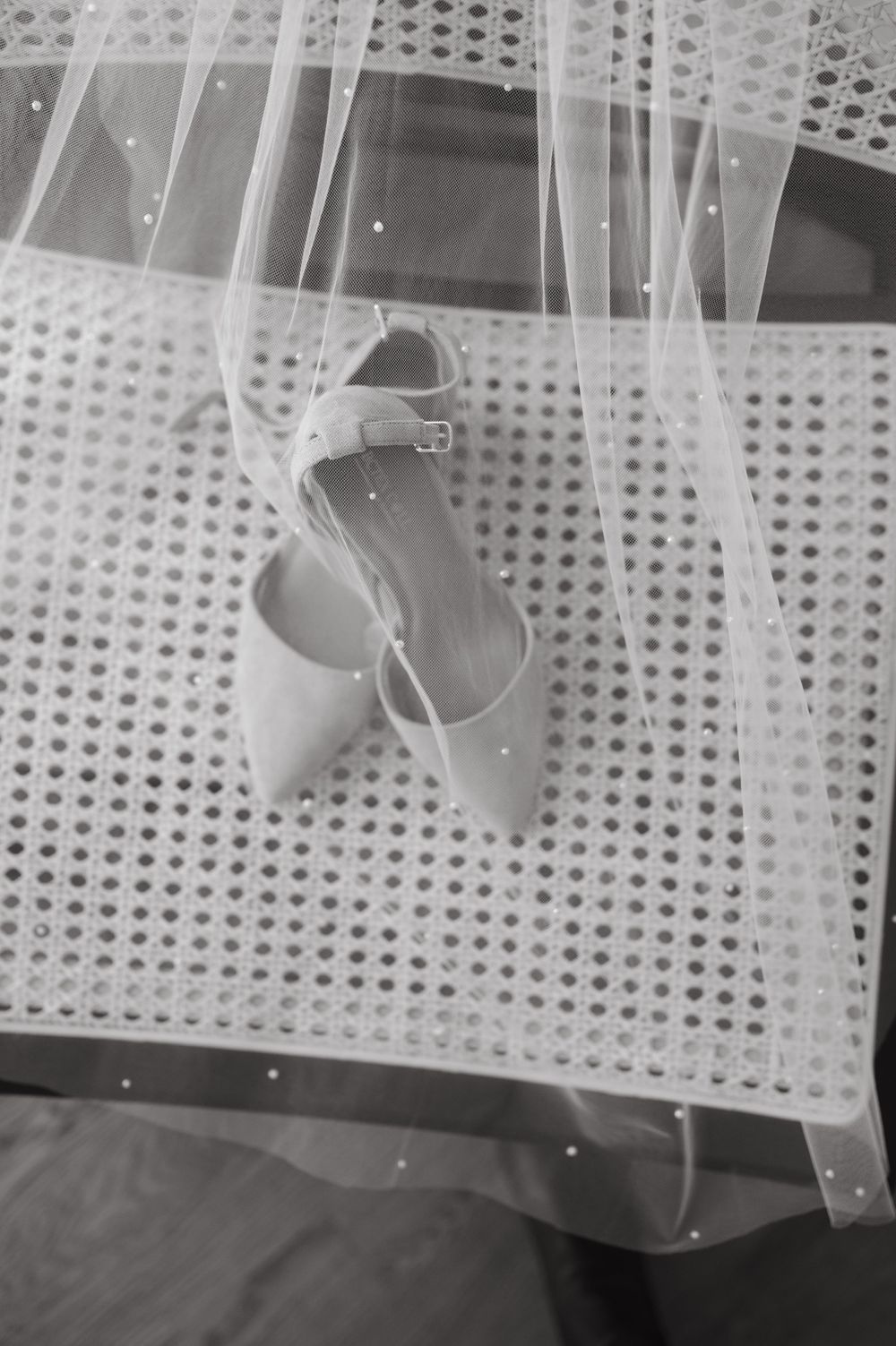 Wedding shoes and veil photographed in black and white with delicate lace details.