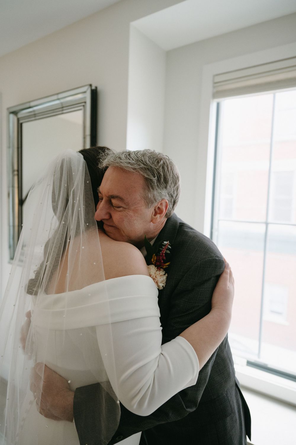 An emotional embrace during a wedding ceremony in a modern, light-filled room.