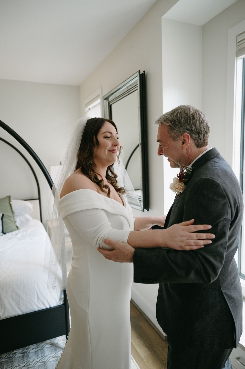 A sweet embrace shared between couple during wedding preparations in a bright bedroom.