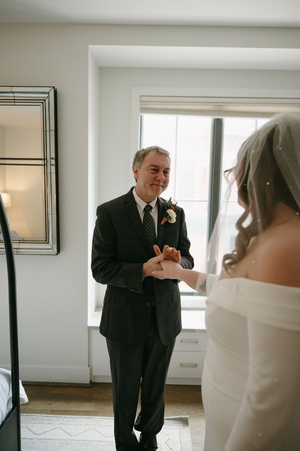 An intimate wedding moment with couple exchanging words by a bright window.