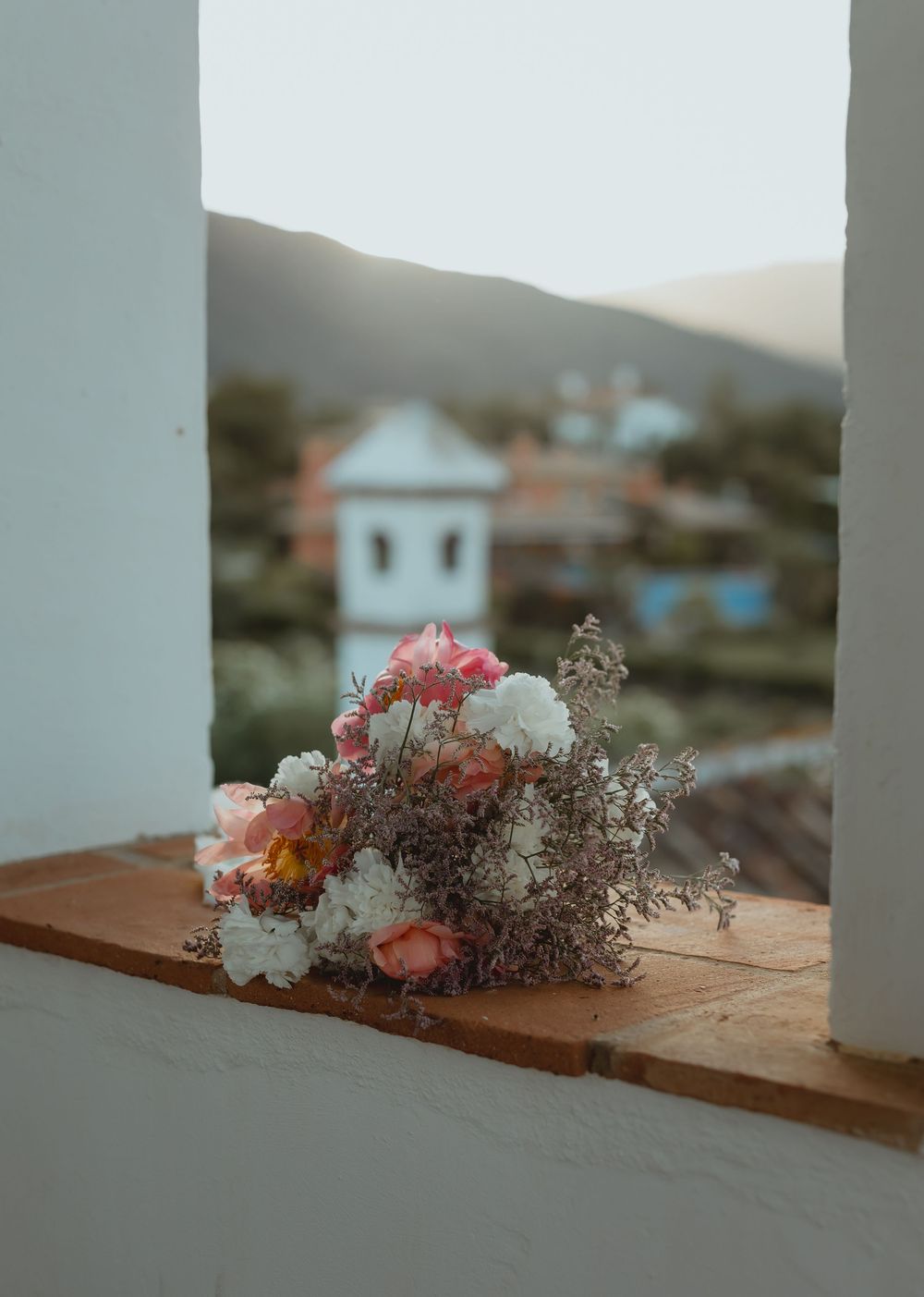 Fresh floral arrangements with pink and white blooms displayed along wooden surfaces at sunset.