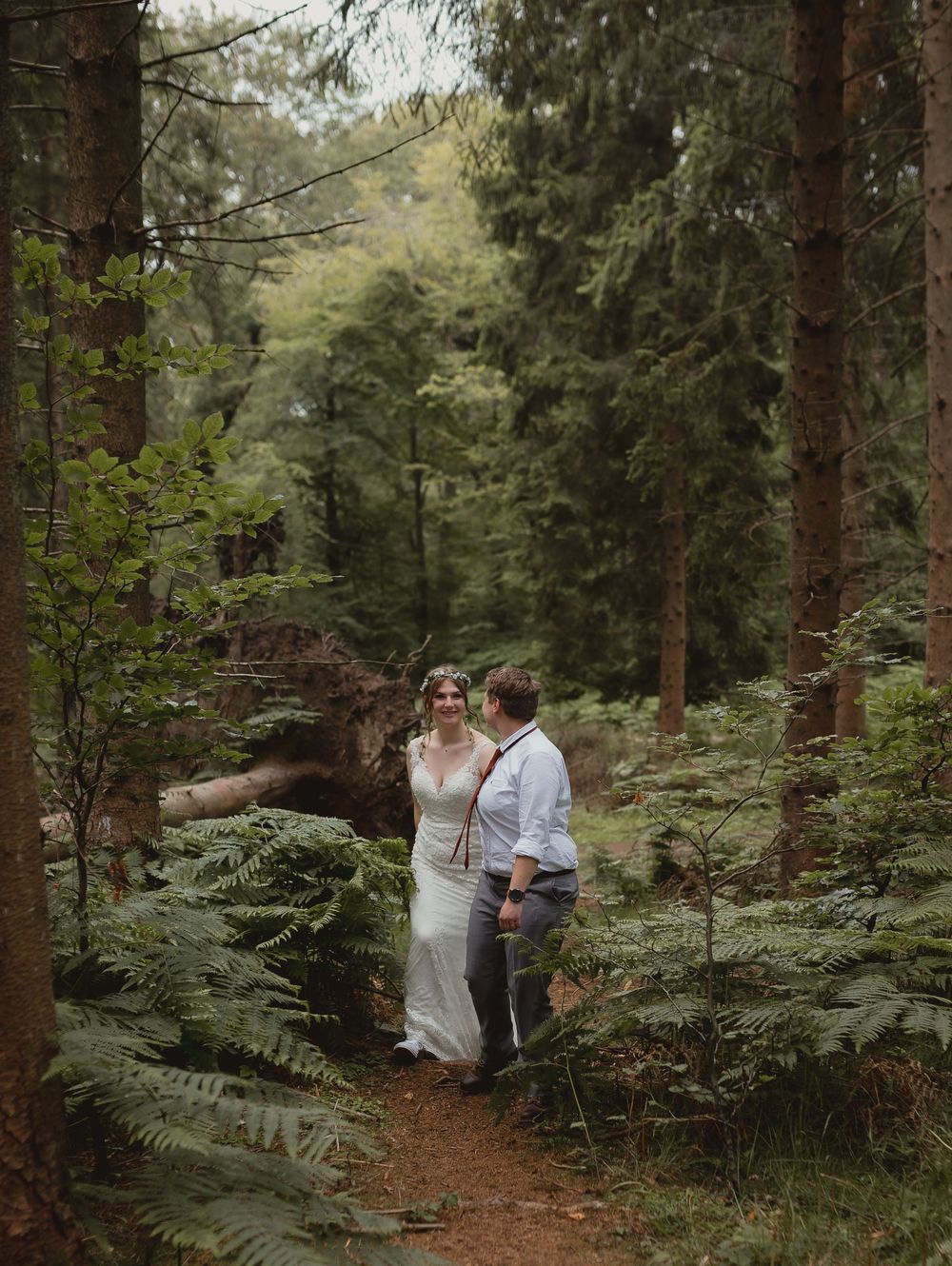 Romantic woodland photoshoot with lush ferns and towering evergreen trees creating a natural forest backdrop.