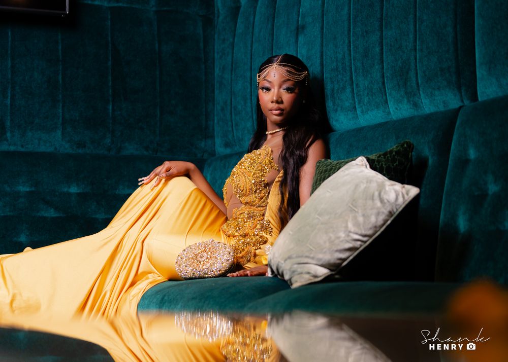 Glamorous evening photo on teal couch wearing gold fitted dress with beaded details.