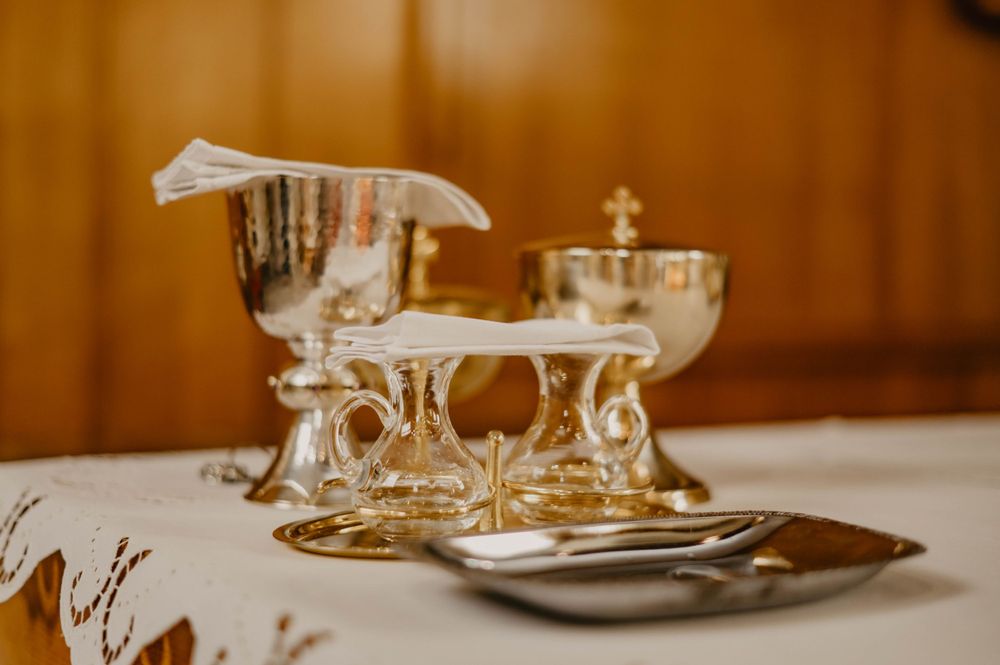 Ornate silver and gold communion vessels arranged on white linen.