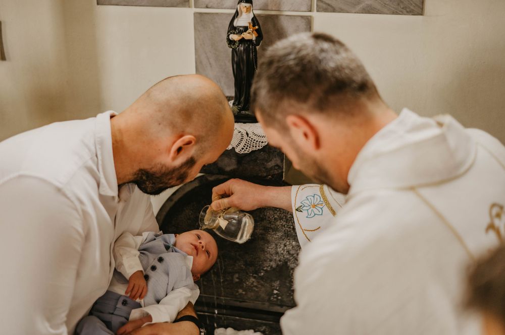Two priests in white robes performing a baptismal ritual.