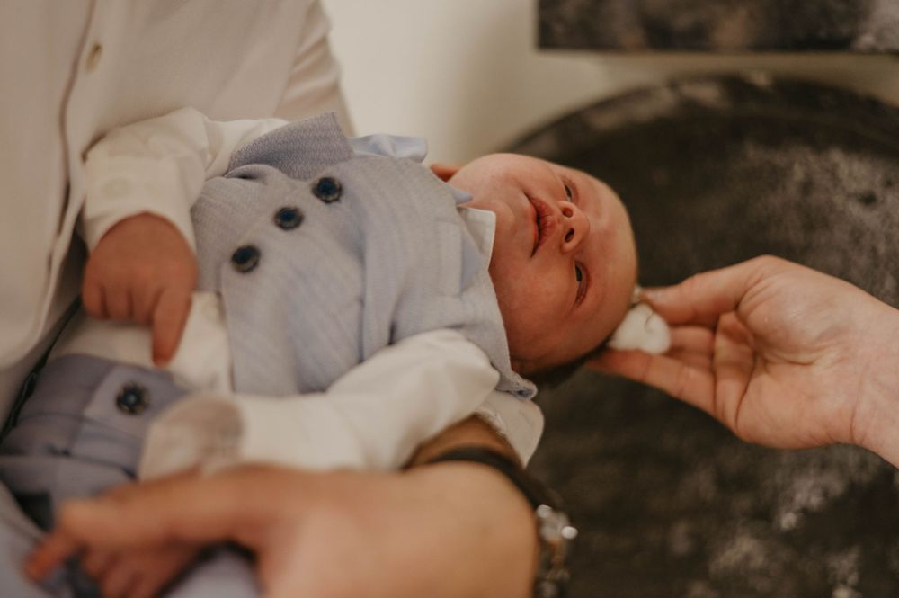 Close-up of a baby in white baptismal clothing during a religious ceremony.