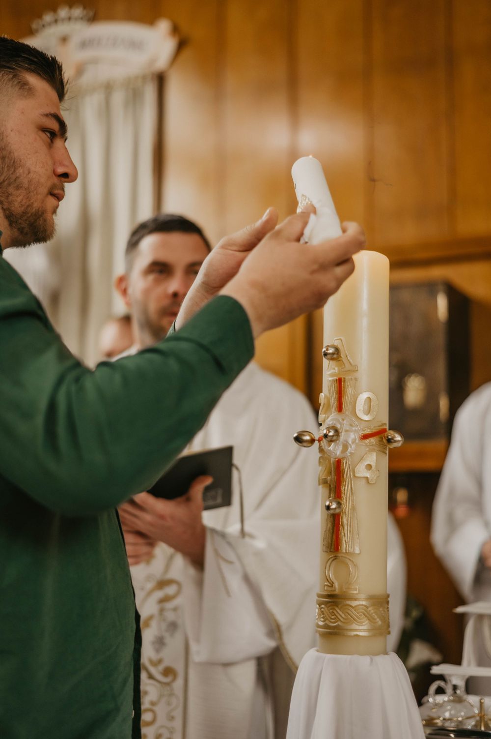 Godparents lighting a ceremonial baptism candle during the church service.