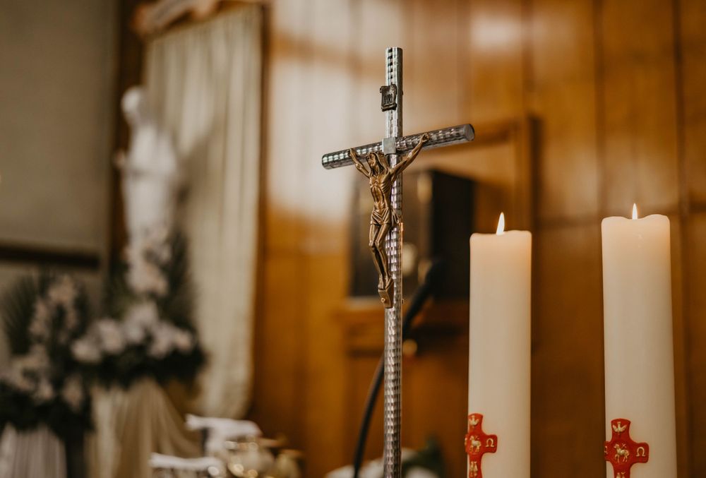 Ornate metal crucifix displayed between two white candles on an altar.