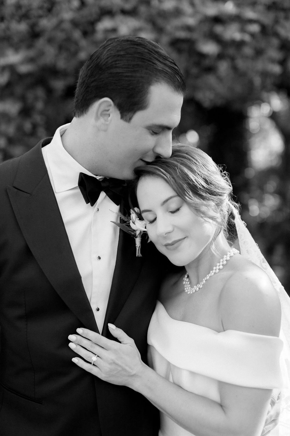 An intimate black and white wedding portrait showing a tender moment between newlyweds.