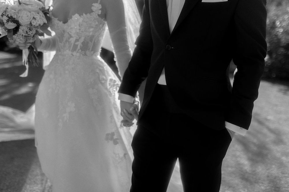 Black and white photo of newlyweds holding hands during outdoor ceremony.