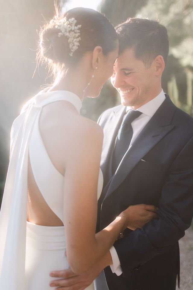 Sun-kissed portrait of a bride and groom sharing an intimate moment outdoors.