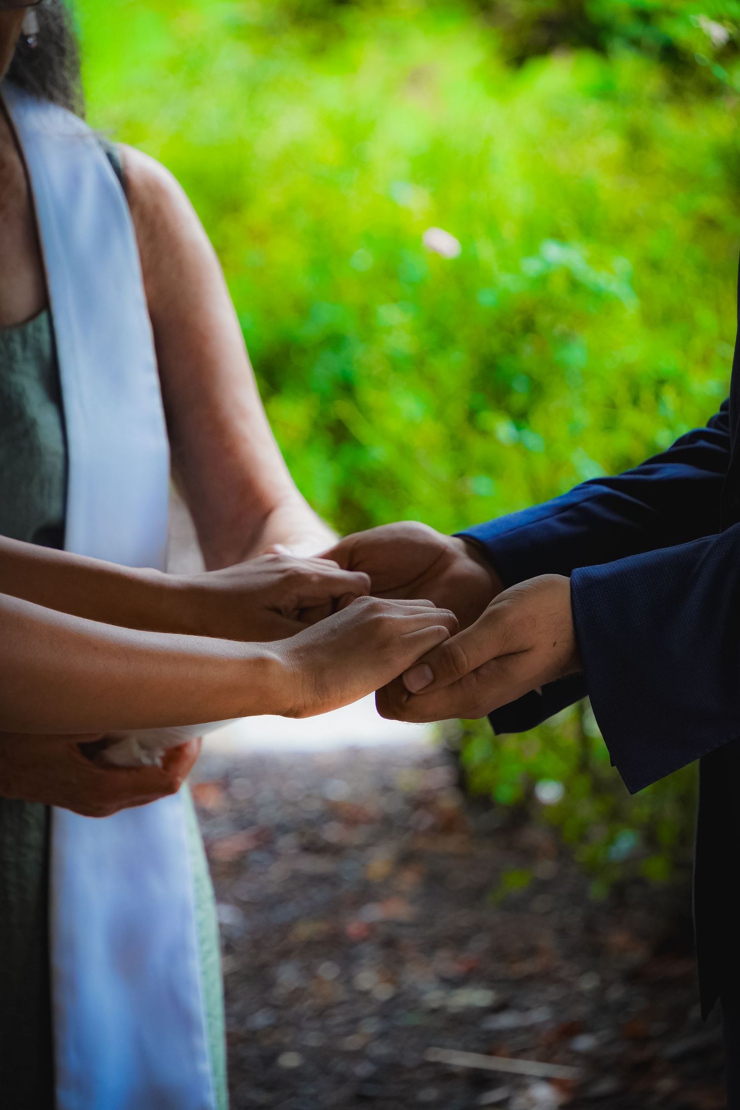 Close up of hands joining together during outdoor ceremony.
