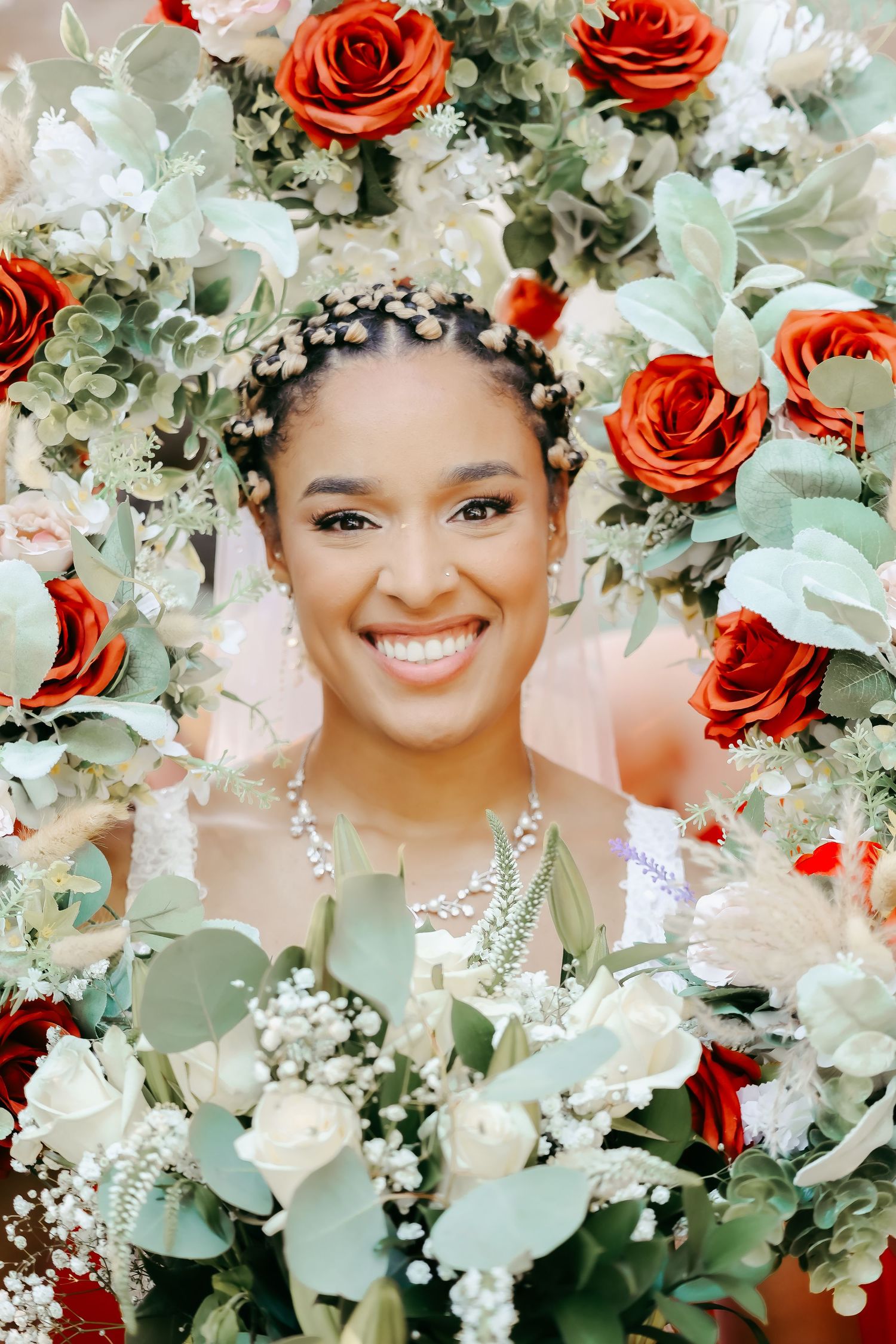 A floral portrait surrounded by red roses and white flowers with delicate greenery.