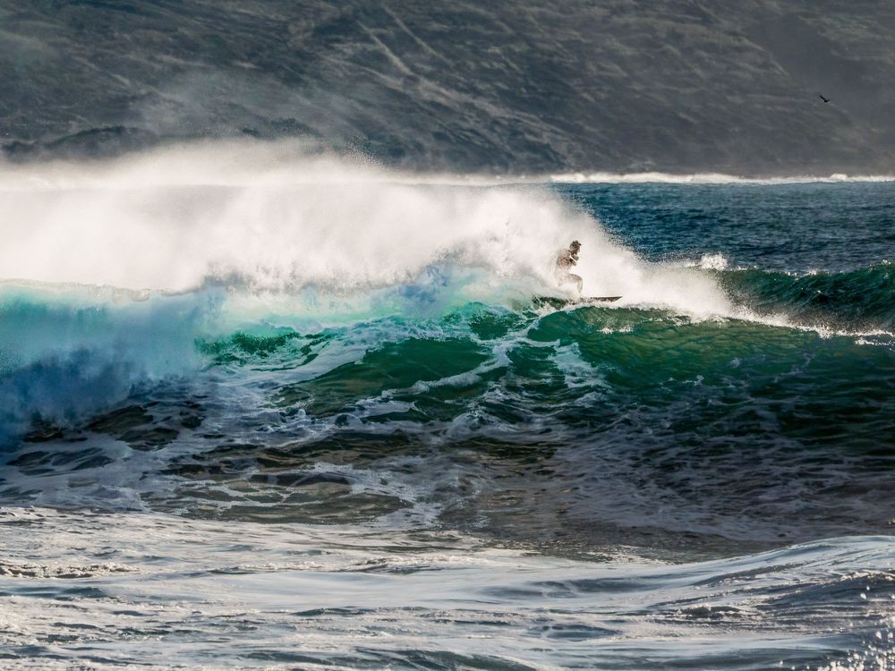 Powerful ocean waves crash and curl with turquoise water and white foam on a stormy day at sea.