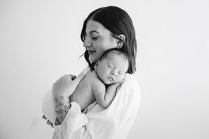 Tender moment between parent and newborn baby in minimalist studio setting.