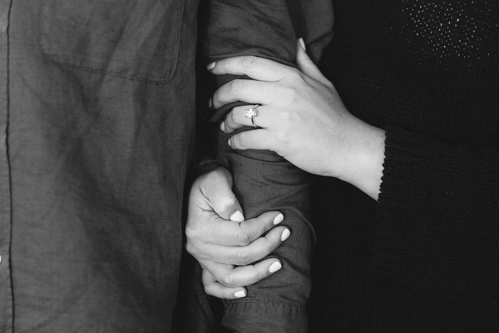 Close-up details of hands during an emotional proposal moment.