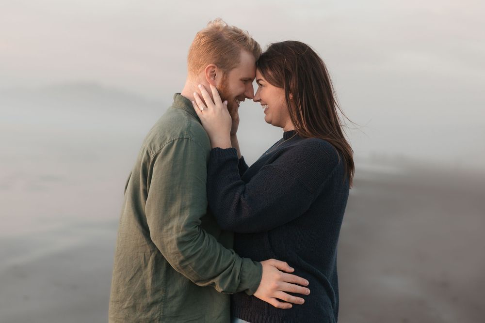 A couple shares an intimate moment together against a misty gray background during a romantic photoshoot.