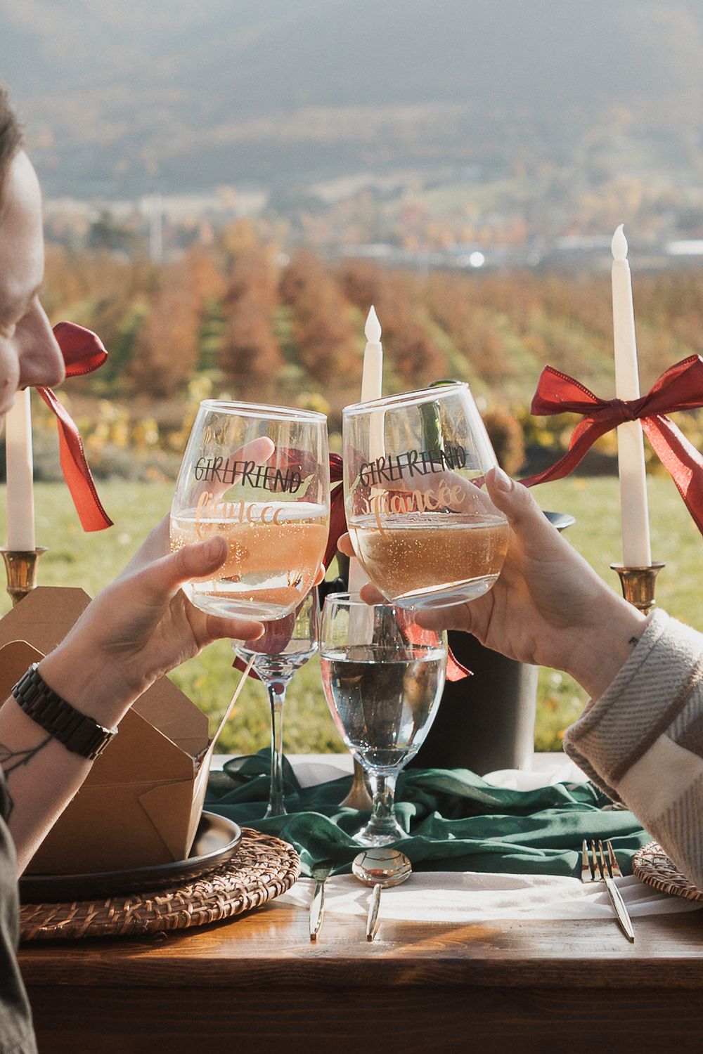Place settings with wine glasses and candles on a rustic table overlooking an autumn mountain landscape.