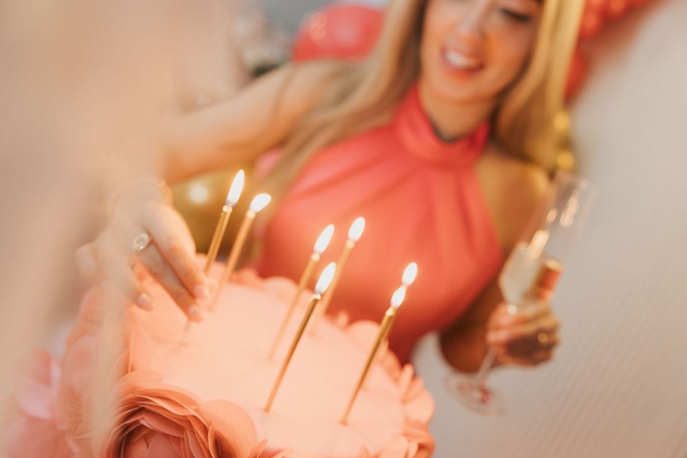 A pink-tinted collection of candlelit celebration moments showing hands, cake and birthday festivities.