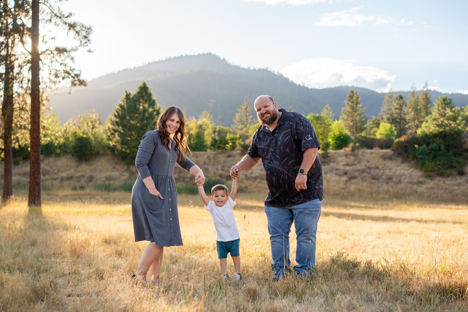 Family of 3 walk together at Pacifica in Williams, Oregon with mountains and trees in the background.