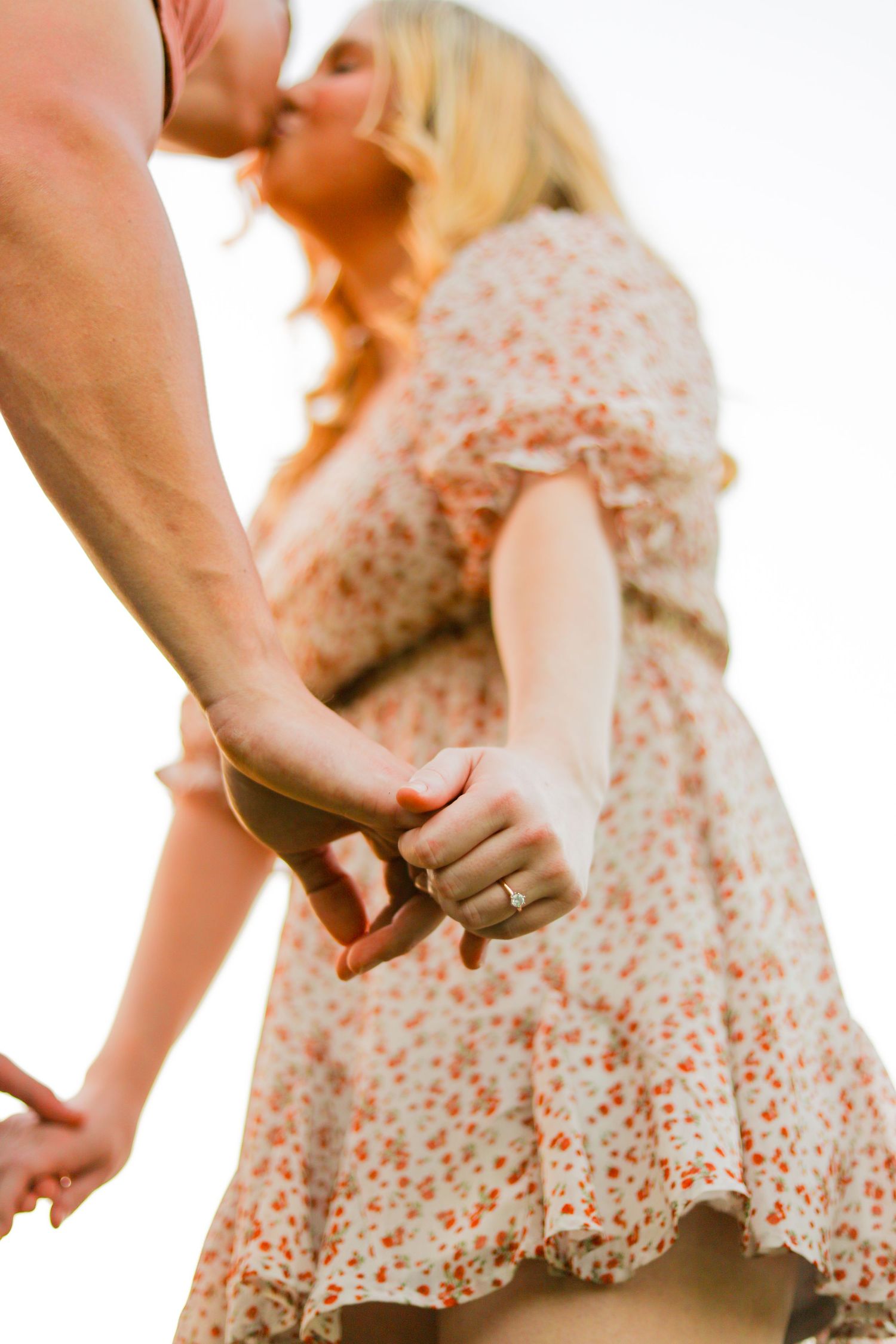 A romantic close-up shot of a couple holding hands while wearing summer attire in soft lighting. Geneva, Florida