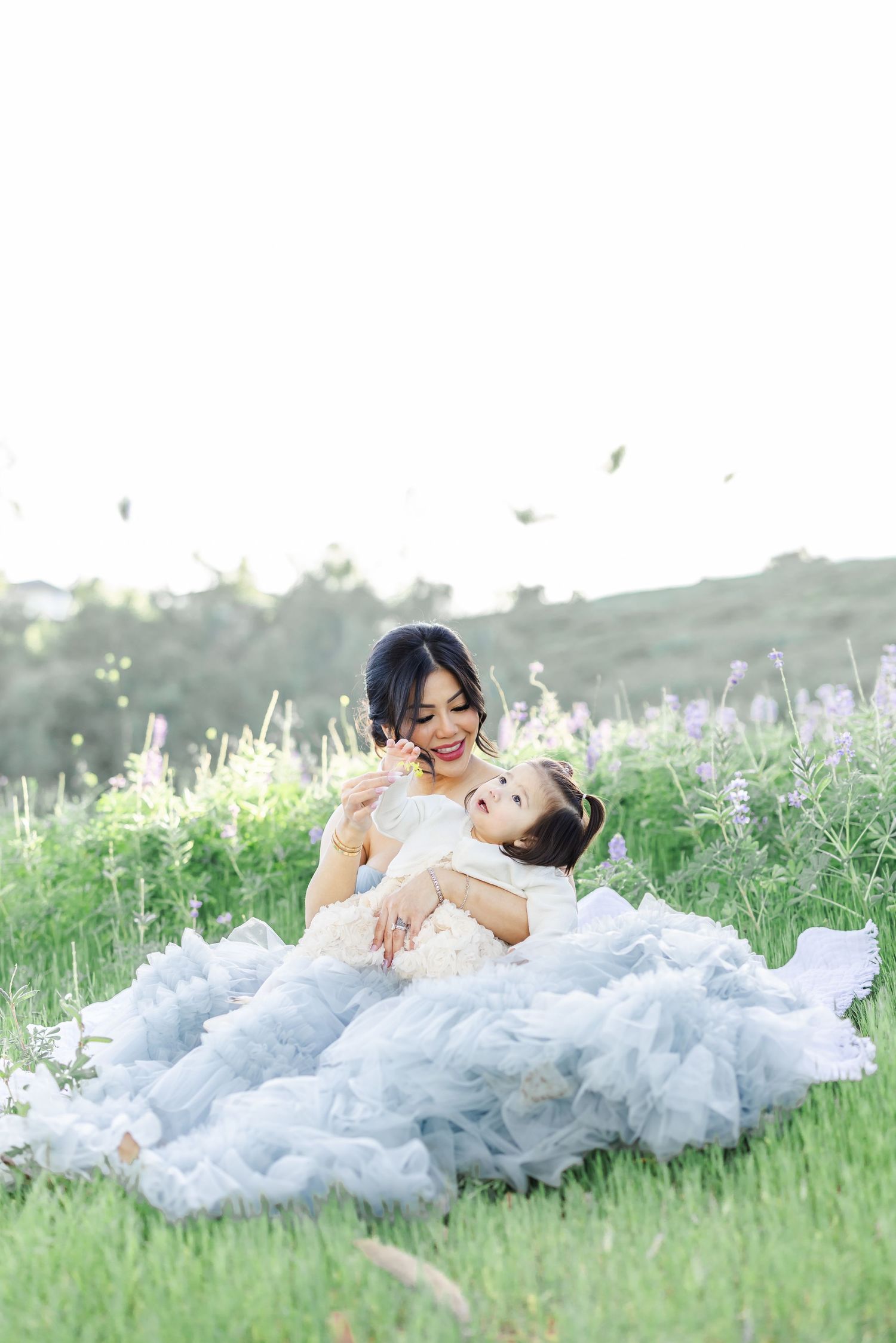 Family portrait in a wildflower meadow with sunflowers and purple blooms at sunset.