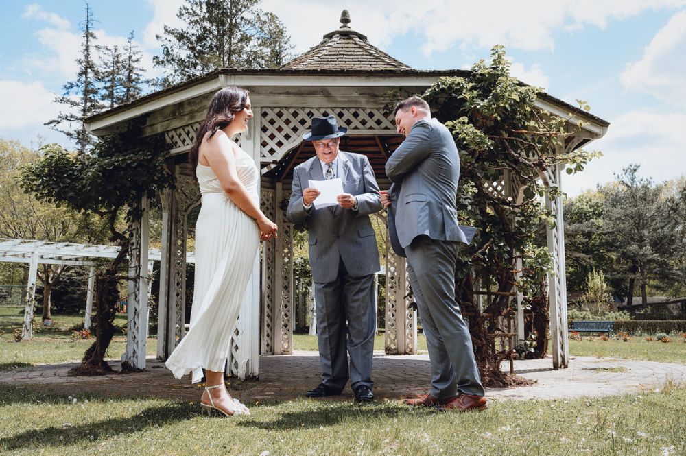 An intimate outdoor wedding ceremony taking place under a white gazebo.
