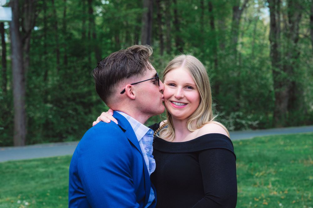 A sweet outdoor moment between a couple with one giving a kiss on the cheek.