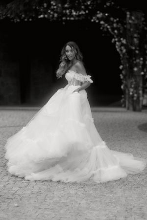 A black and white portrait of someone twirling in a flowing princess-style wedding gown.