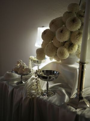 White chrysanthemum flowers in a glass vase catch dramatic lighting against a dark background in a moody still life series.