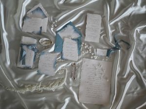 Handwritten notes and papers scattered across a reflective metallic surface create an artistic composition.