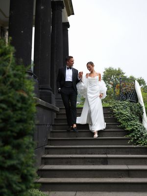 A couple descends outdoor stone steps together during a wedding photo session, with greenery visible in the background.