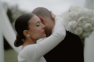A tender moment captured between two people in elegant white wedding attire.