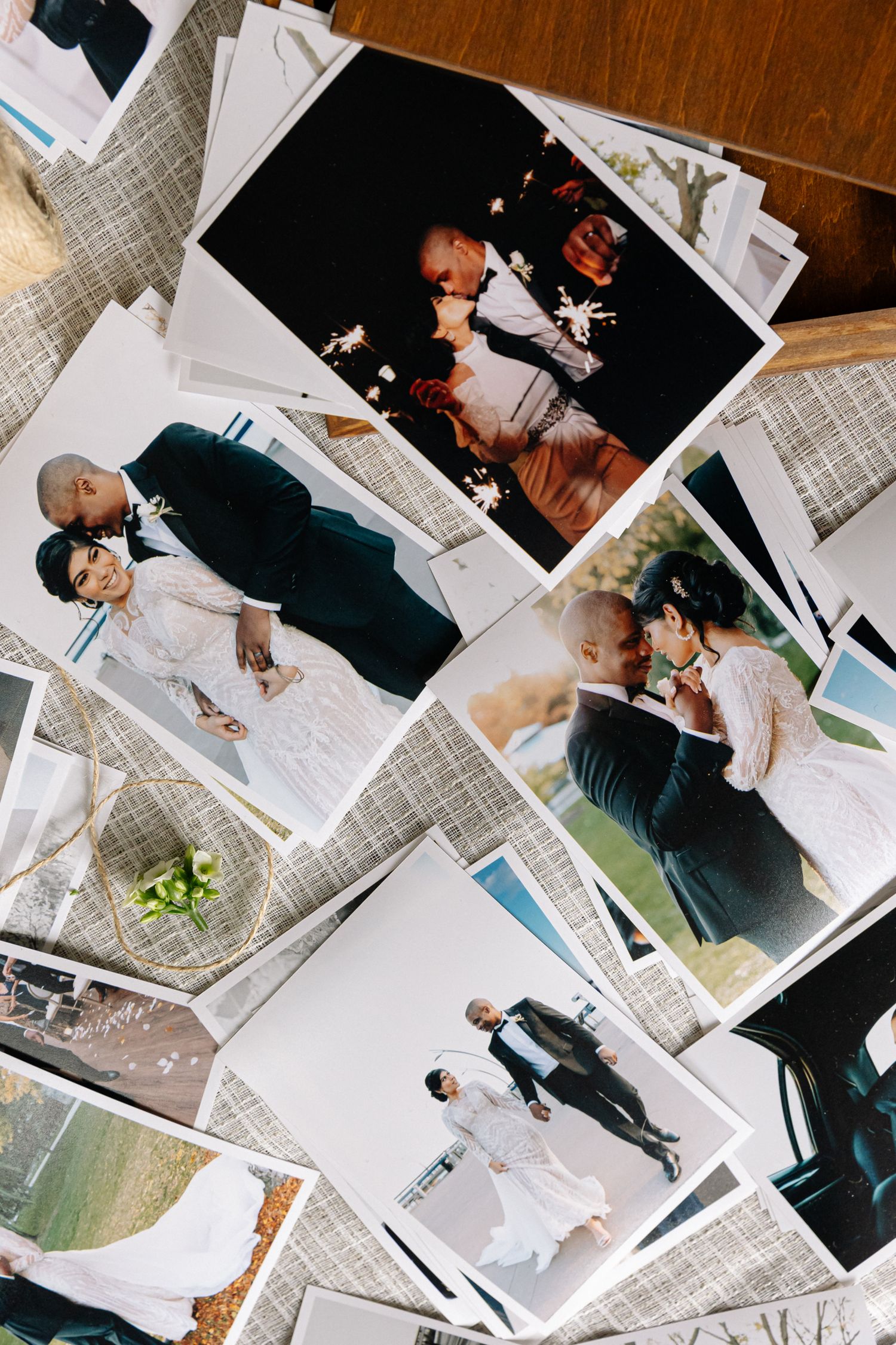 Collection of wedding photographs spread out on textured fabric surface.