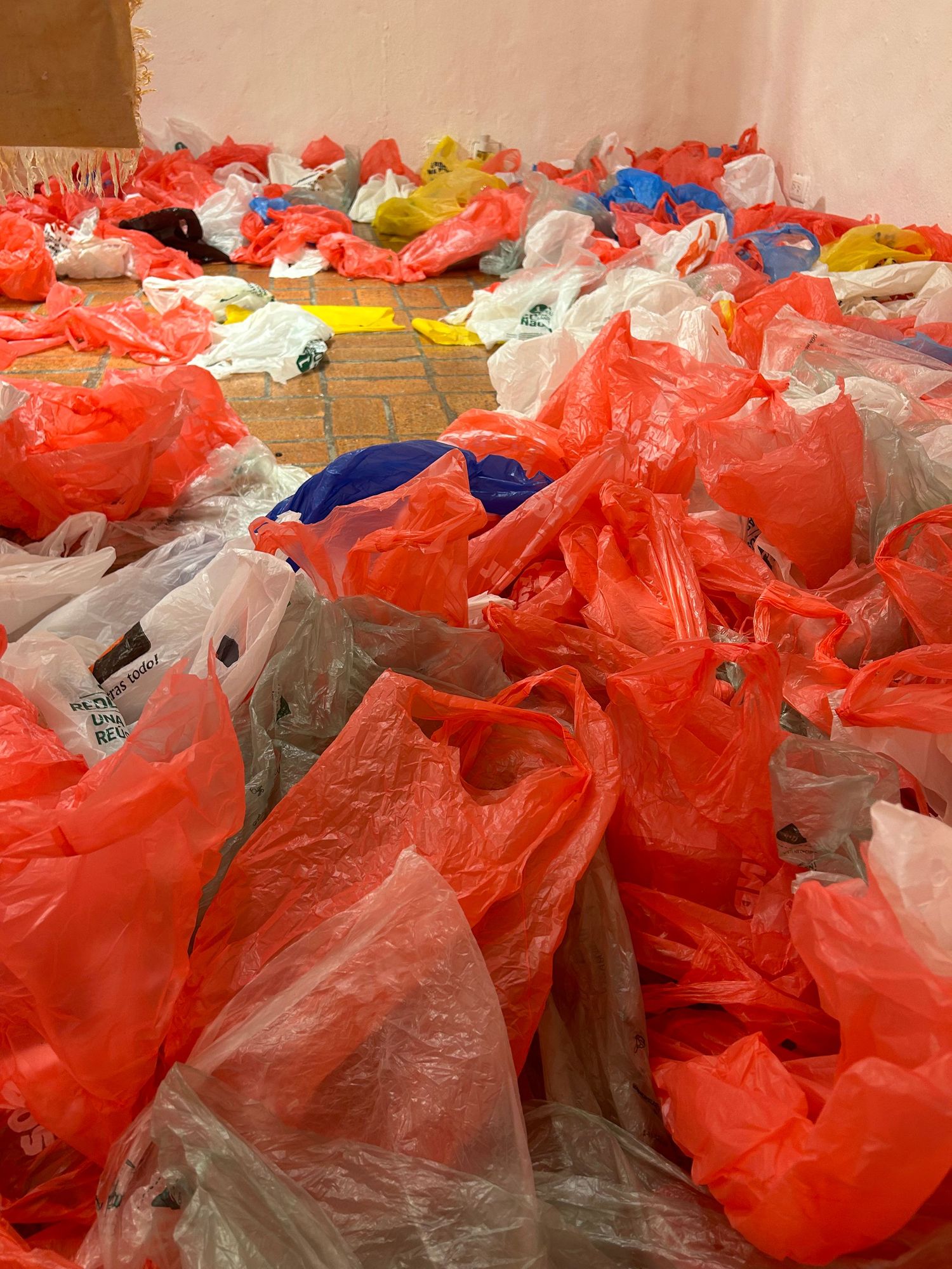 Collection of crumpled plastic bags in red, white, and blue creating a textural installation.