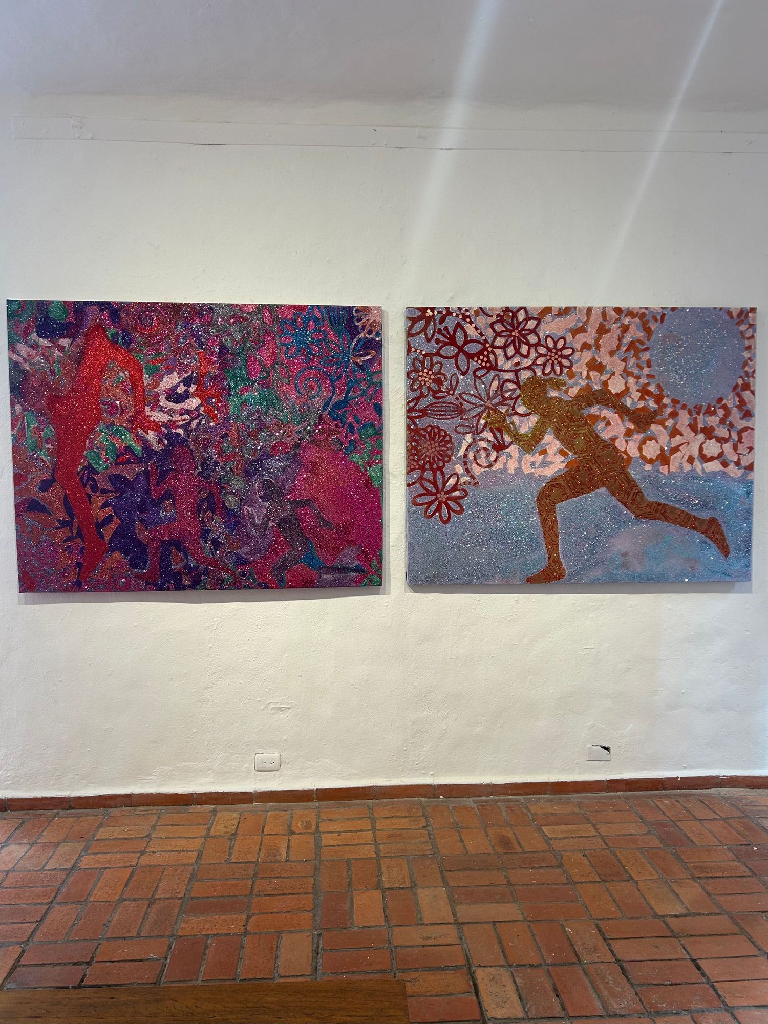 Abstract art gallery display showing two vibrant paintings, one with red and purple swirls and another featuring flowing patterns.