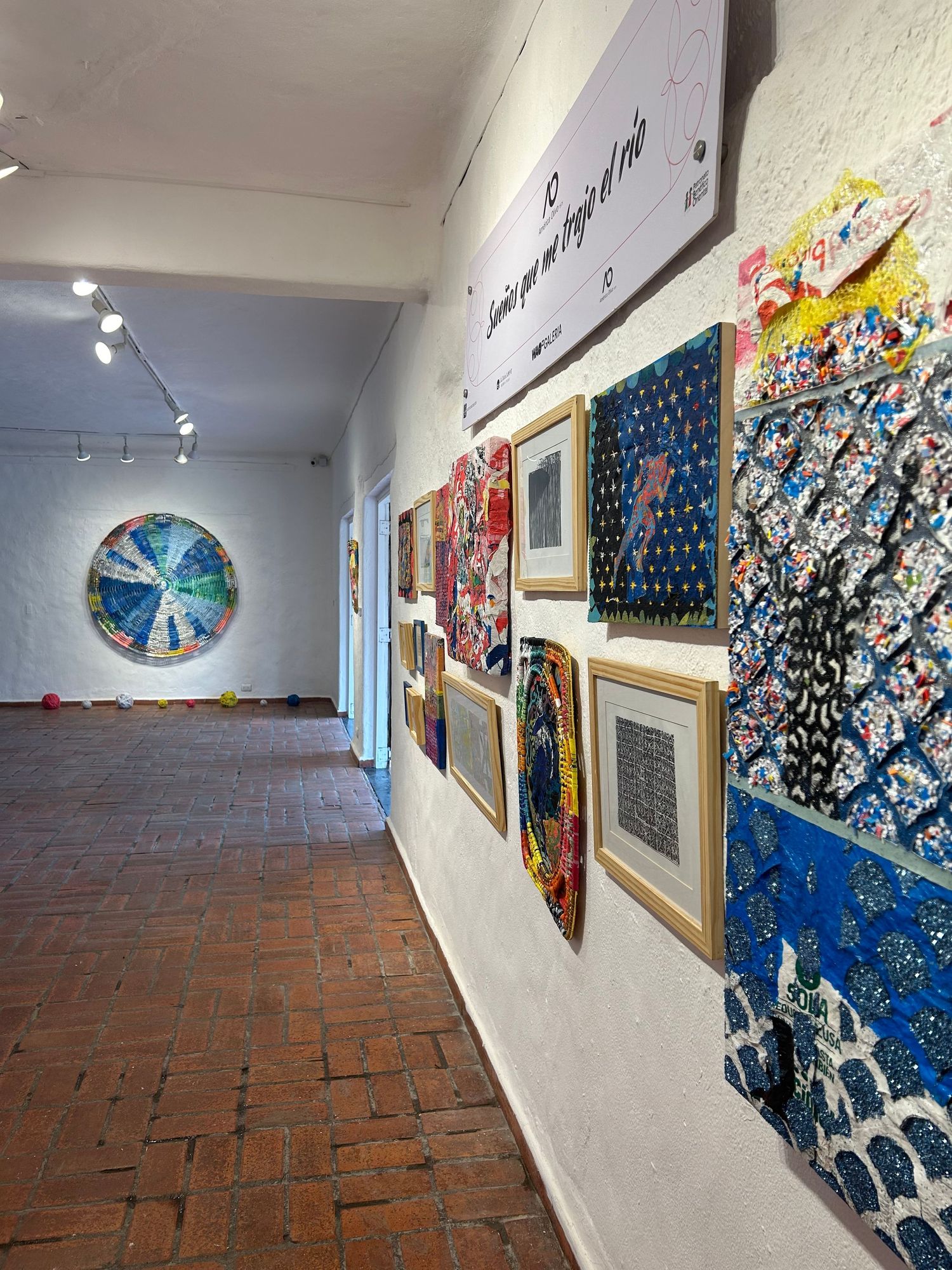 Long gallery corridor with circular artwork and diverse wall displays on white walls.