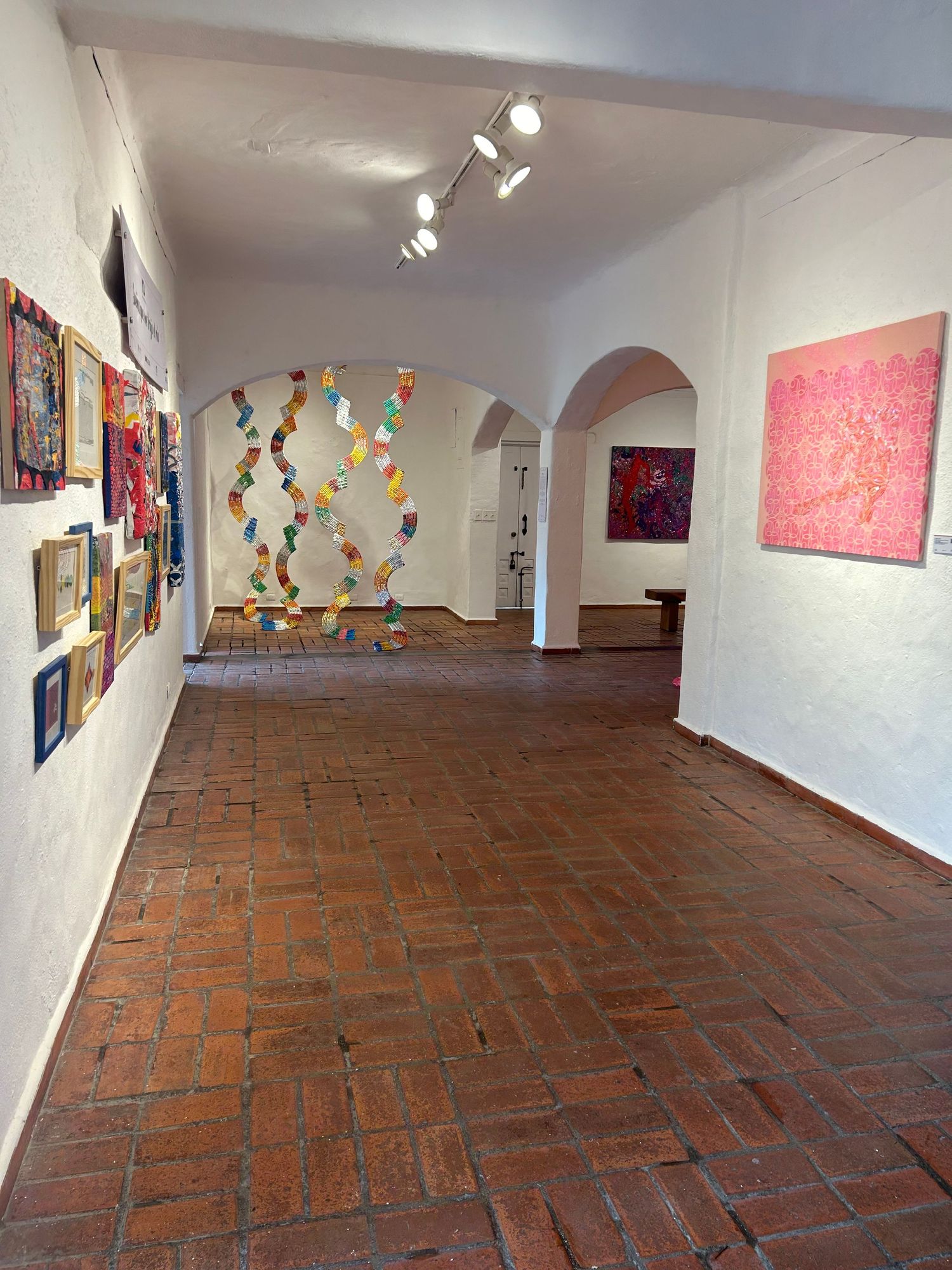 Modern gallery space with suspended geometric installation and contemporary artworks on display.