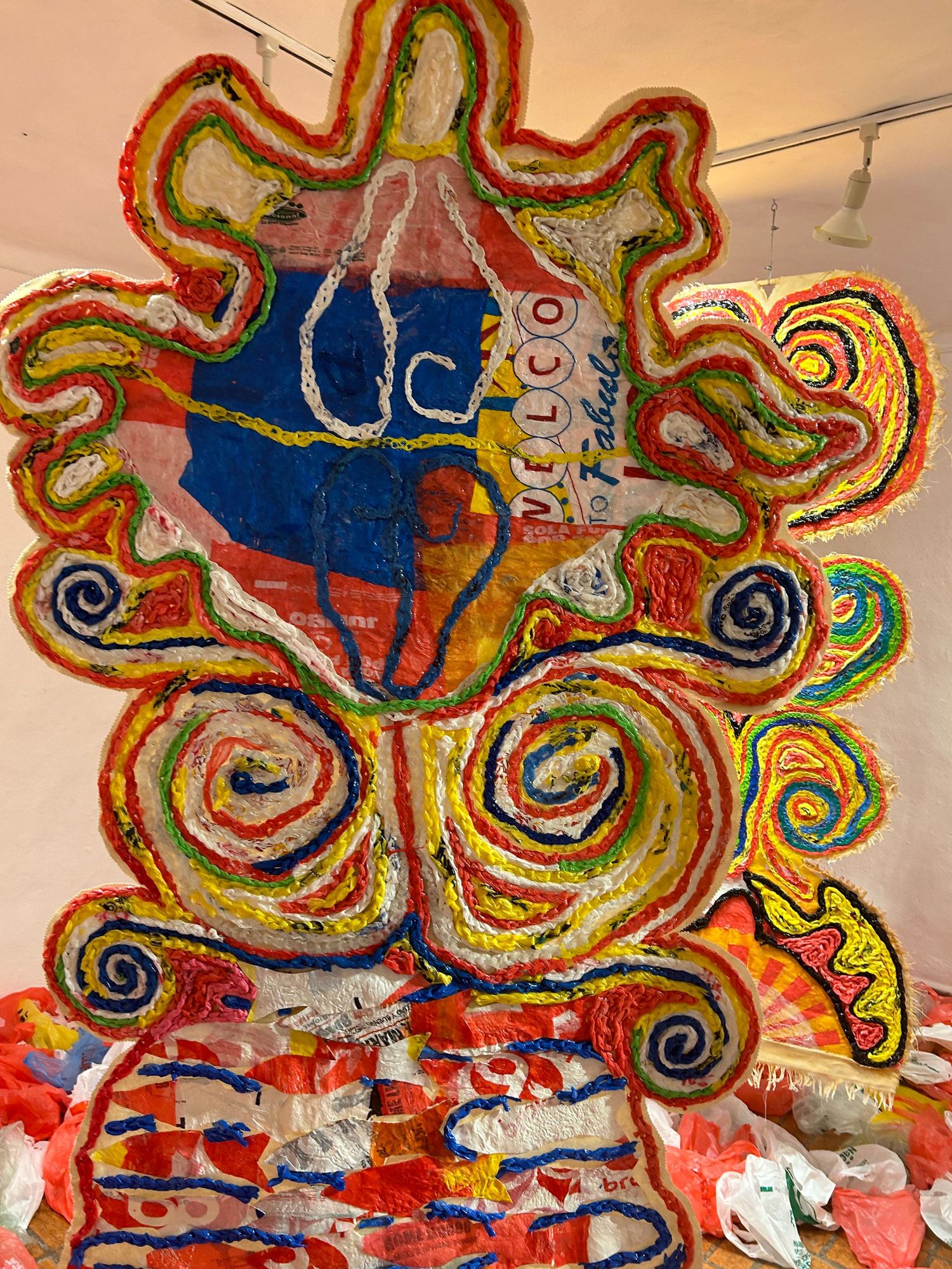 Whimsical plastic art piece featuring swirling designs and bottle shape in bright colors.