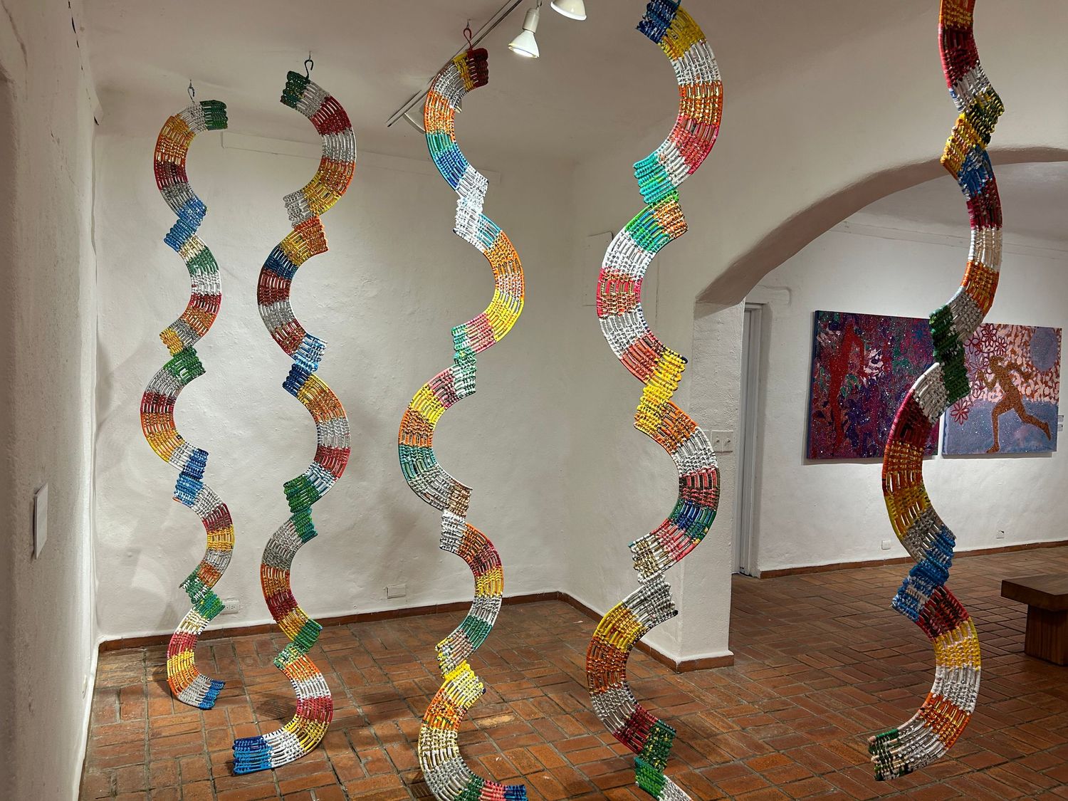 Colorful spiral paper decorations hanging from ceiling in art gallery space.