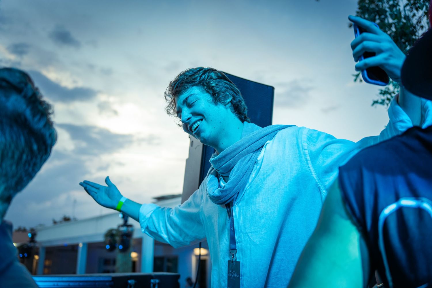 Performer illuminated in blue light during outdoor evening event.