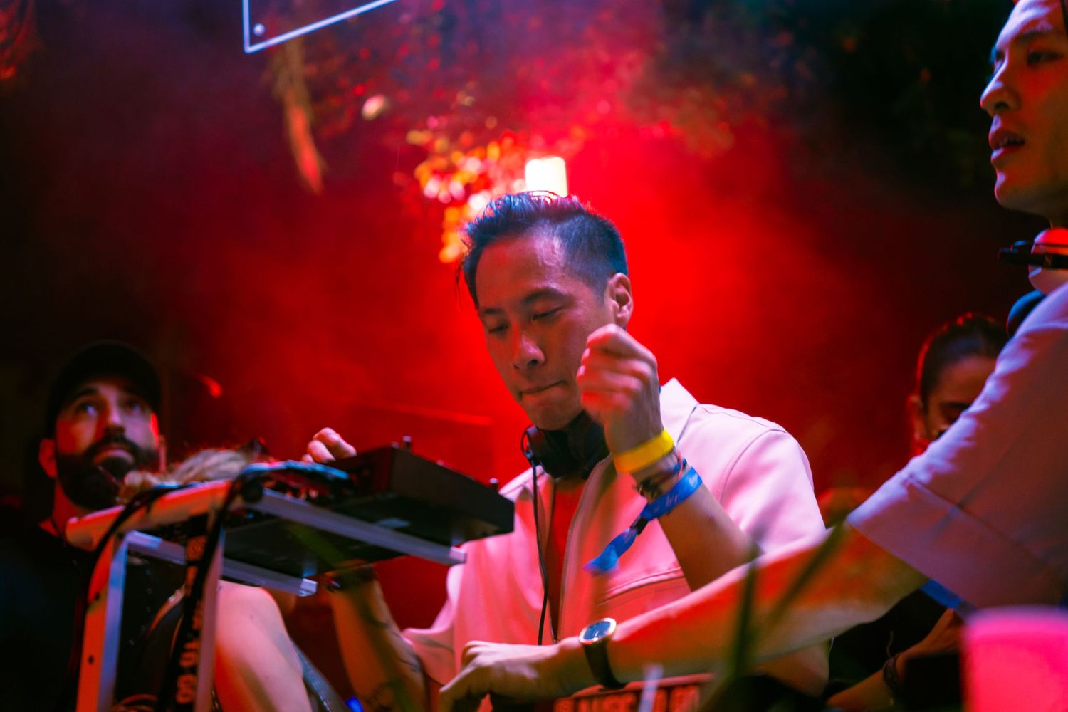Musician performing under dramatic red stage lighting with electronic equipment.