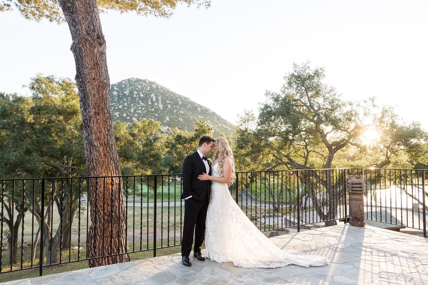 Wedding couple poses together during sunset in a scenic outdoor setting at mt woodson castle in Ramona, CA.