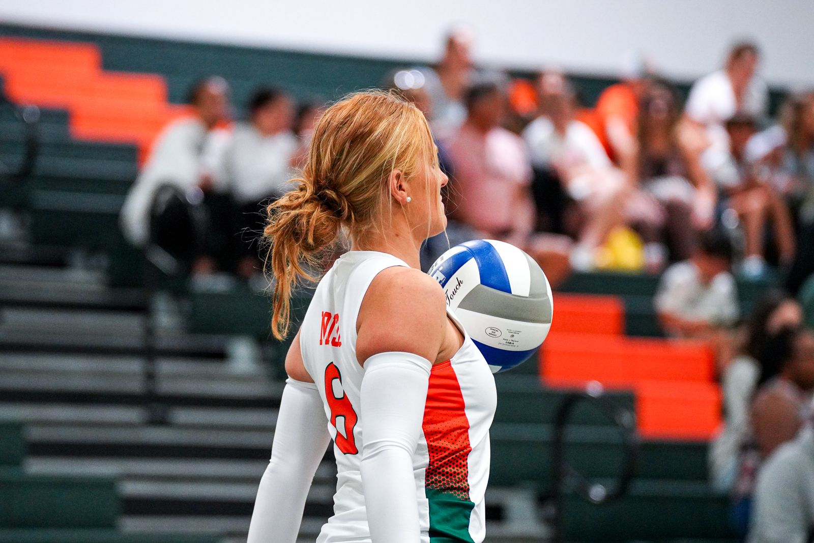 Female volleyball player in white jersey holding ball during match.