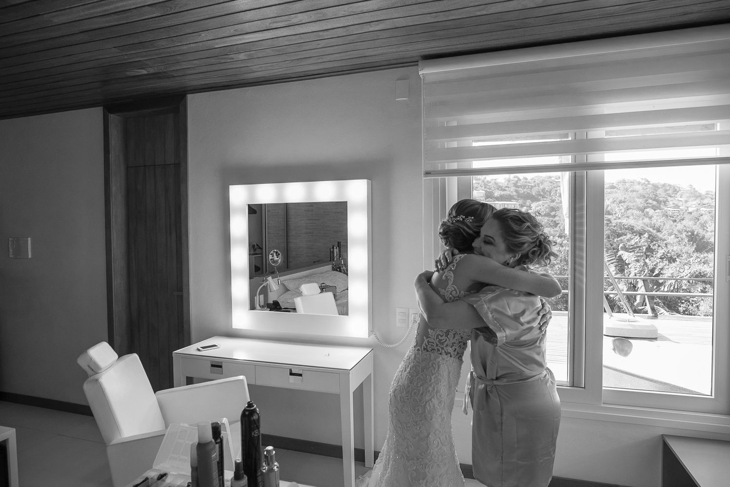 Black and white candid moment captured in bright interior space with vanity mirror.